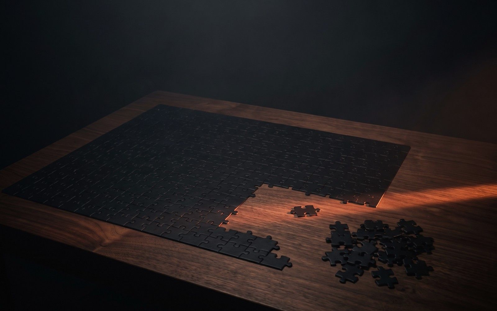 A black jigsaw puzzle about seventy per cent assembled on a walnut table, loose pieces beside the gap
